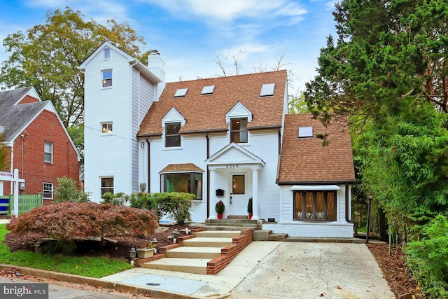 view of front of home with a shingled roof and brick siding