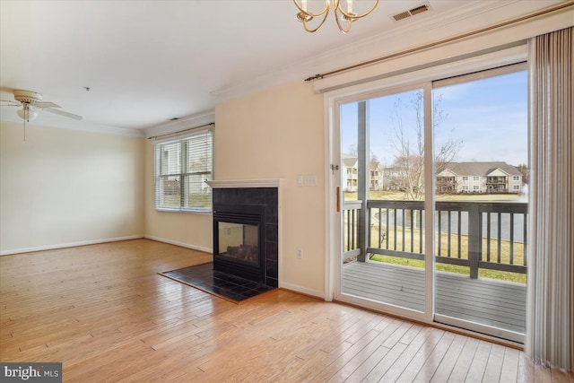 unfurnished living room with a fireplace, visible vents, ornamental molding, wood finished floors, and baseboards