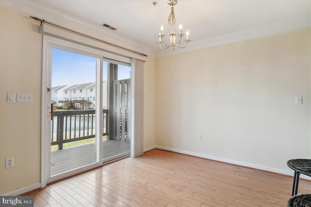 empty room with wood-type flooring, visible vents, ornamental molding, a chandelier, and baseboards