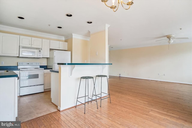 kitchen with white appliances, a kitchen breakfast bar, open floor plan, dark countertops, and crown molding