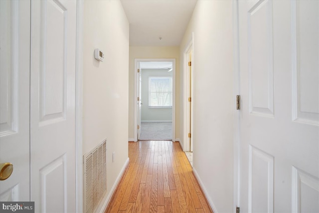 hall featuring light wood-style floors, visible vents, and baseboards