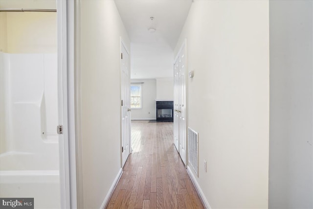 corridor with wood finished floors, visible vents, and baseboards