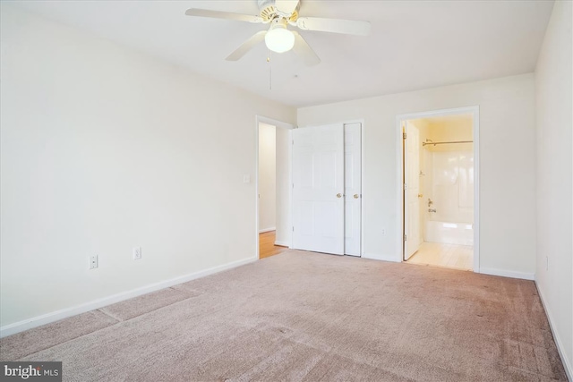 unfurnished bedroom featuring carpet, baseboards, ceiling fan, and ensuite bathroom