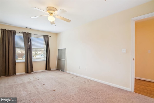 carpeted spare room featuring a ceiling fan and baseboards