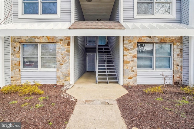 doorway to property with stone siding and roof with shingles