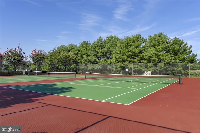 view of tennis court featuring community basketball court and fence