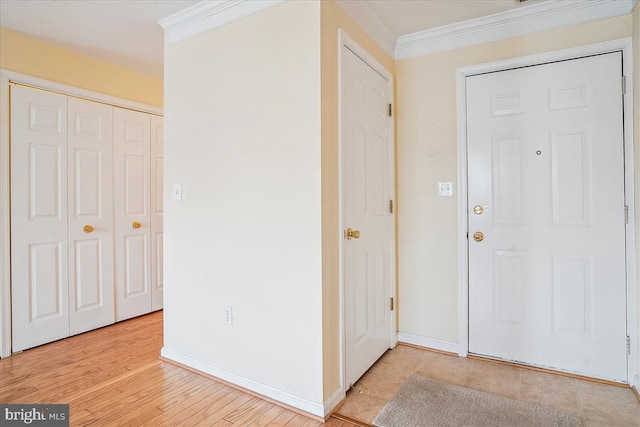 foyer with light wood finished floors, baseboards, and crown molding