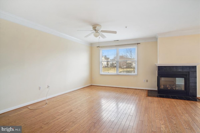 unfurnished living room with baseboards, wood-type flooring, ceiling fan, crown molding, and a fireplace