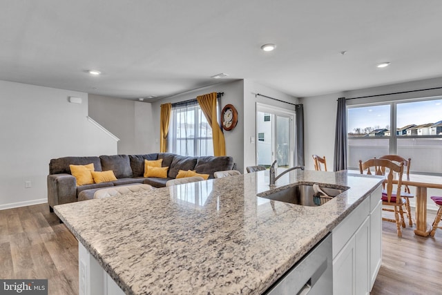 kitchen with a sink, light wood-style floors, dishwasher, and white cabinets