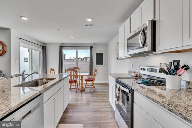 kitchen featuring visible vents, light wood-style flooring, a sink, appliances with stainless steel finishes, and white cabinetry