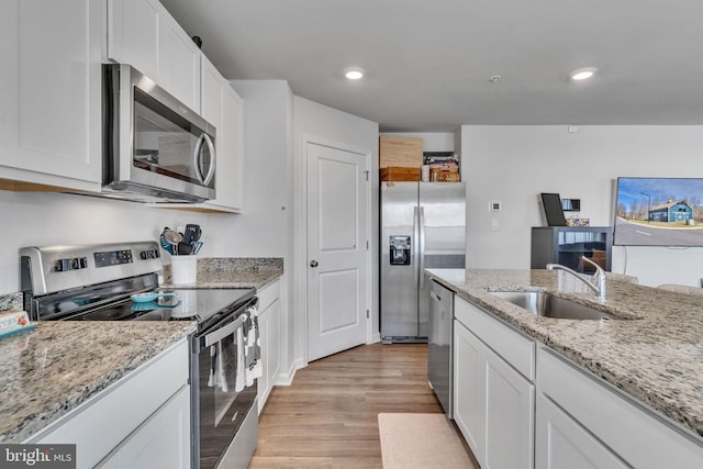 kitchen with a sink, stainless steel appliances, light wood-style flooring, and white cabinetry