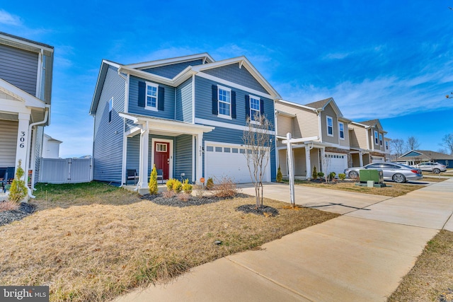 traditional-style home featuring a gate, fence, a residential view, concrete driveway, and an attached garage