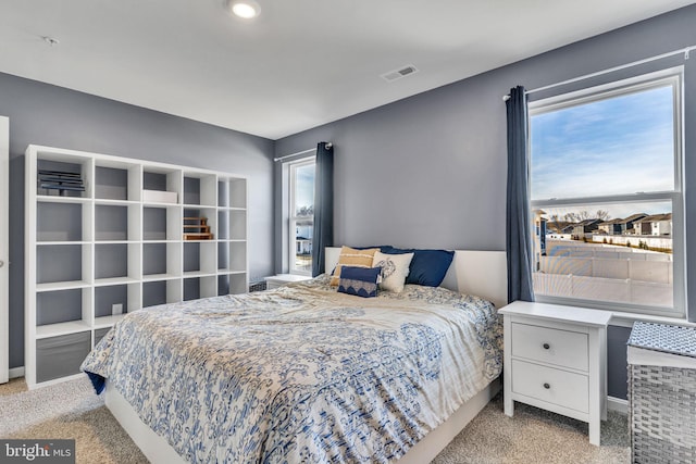 carpeted bedroom featuring visible vents, multiple windows, and baseboards