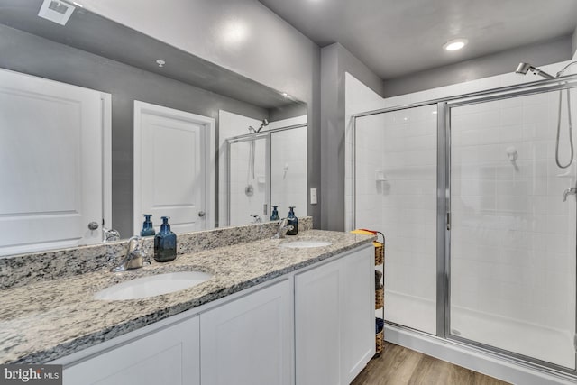 bathroom featuring a sink, visible vents, a stall shower, and wood finished floors