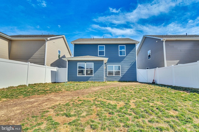 rear view of property featuring a yard and a fenced backyard