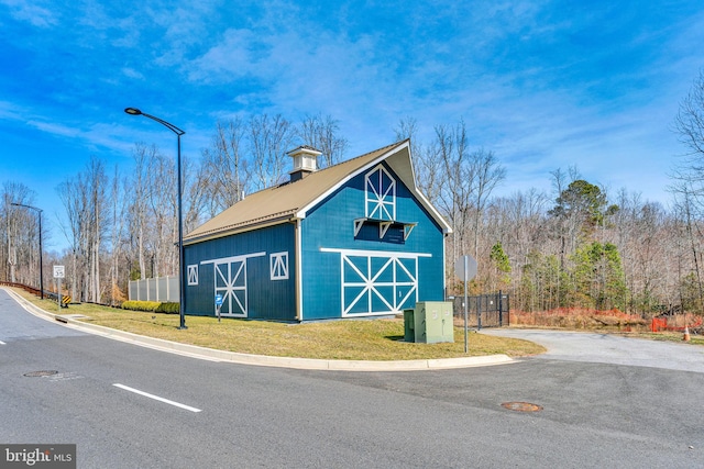 view of barn featuring a yard and fence