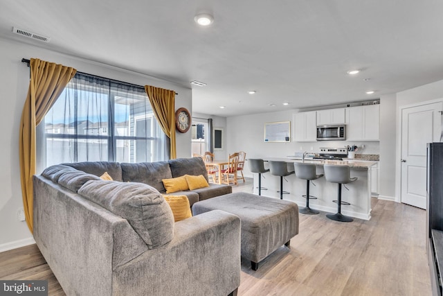 living area featuring light wood finished floors, visible vents, recessed lighting, and baseboards