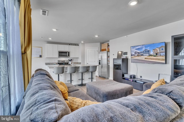 living area with visible vents, recessed lighting, and light wood-type flooring