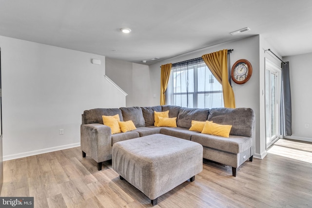 living area with light wood finished floors, visible vents, and baseboards