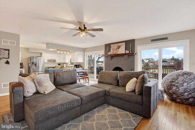 living room featuring visible vents, baseboards, light wood-type flooring, and ceiling fan