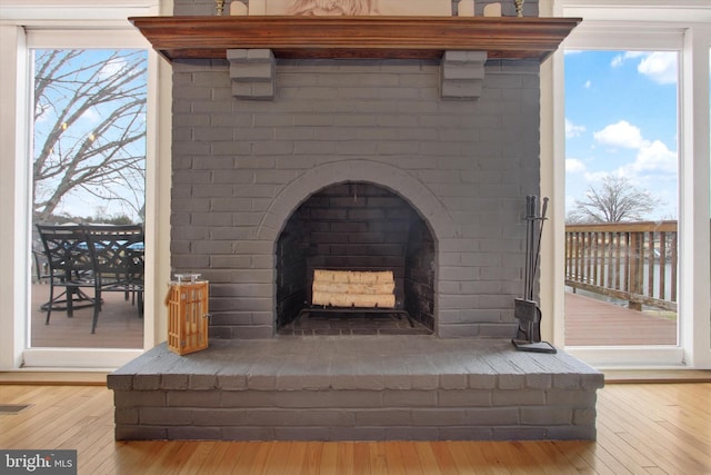 room details with a brick fireplace, wood finished floors, and visible vents