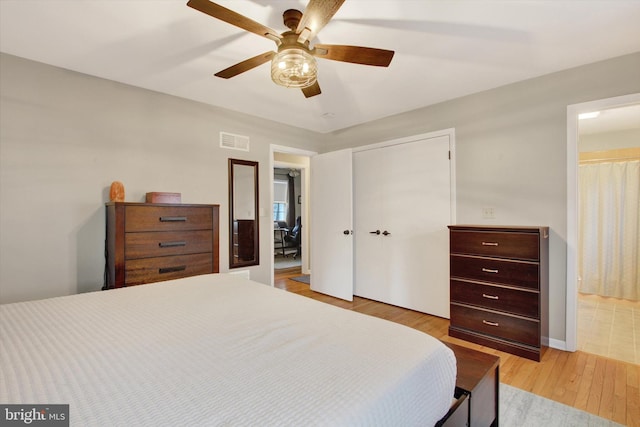 bedroom with visible vents, light wood finished floors, ensuite bath, ceiling fan, and a closet