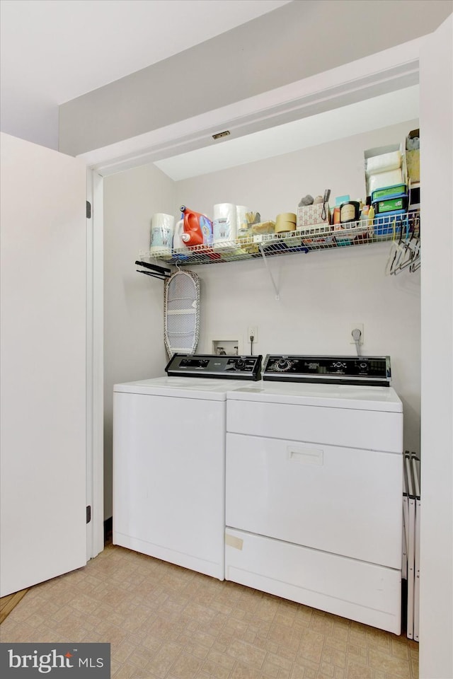 clothes washing area featuring laundry area, washing machine and dryer, and light floors