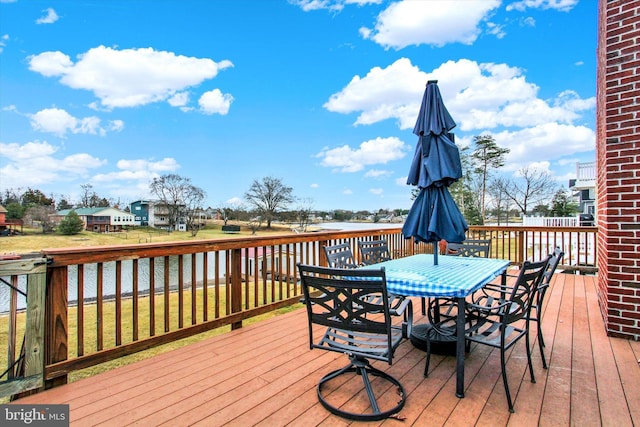 wooden terrace featuring outdoor dining area and a water view