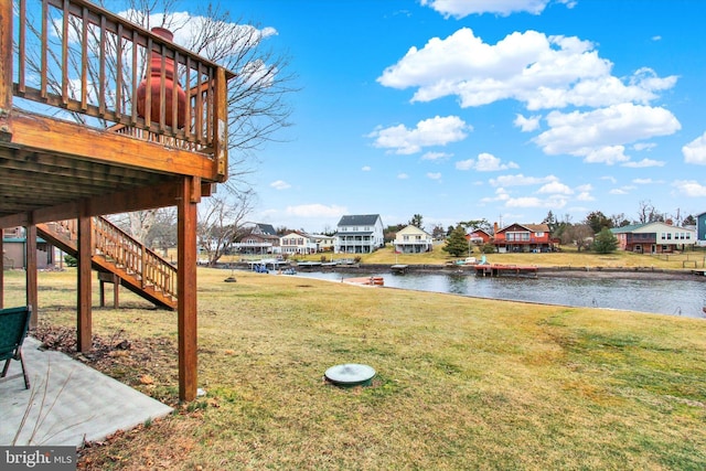 view of yard featuring stairway, a residential view, and a deck with water view