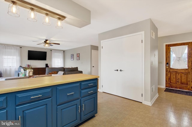 kitchen featuring blue cabinets, visible vents, a ceiling fan, open floor plan, and baseboards