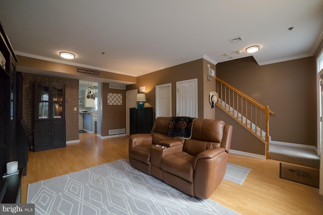 living room with visible vents, stairway, wood finished floors, and ornamental molding