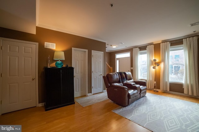 living area with ornamental molding, stairway, light wood-type flooring, and visible vents