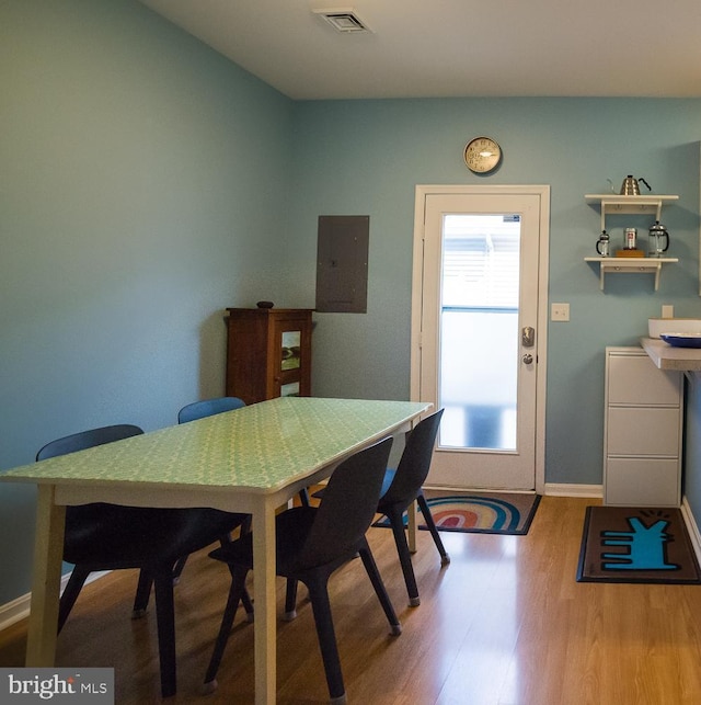 dining room with electric panel, visible vents, baseboards, and wood finished floors