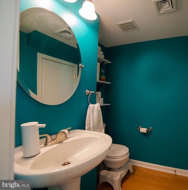 bathroom featuring baseboards, visible vents, a sink, and wood finished floors