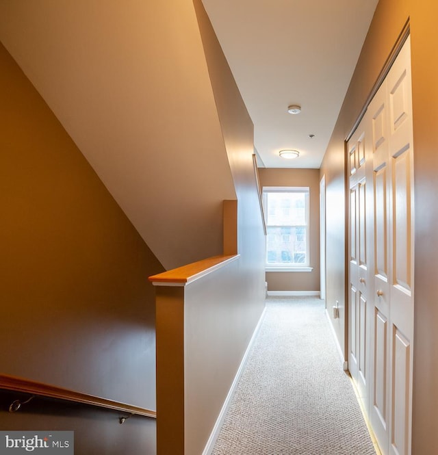 hallway with carpet, an upstairs landing, and baseboards