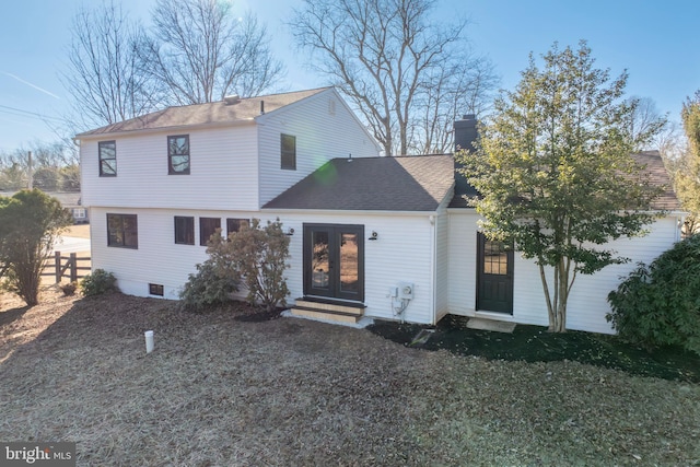 view of front of home featuring entry steps, a shingled roof, fence, french doors, and a chimney