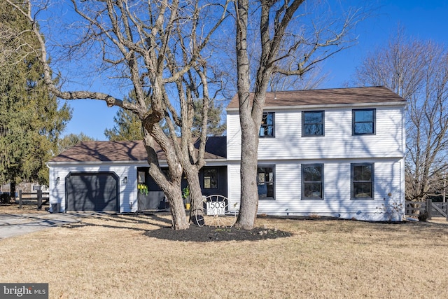 colonial house with concrete driveway, a front lawn, and an attached garage