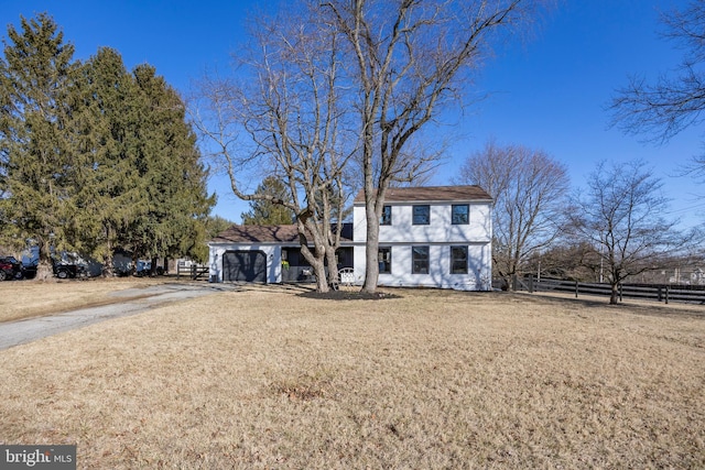 view of front facade with a garage, driveway, a front lawn, and fence