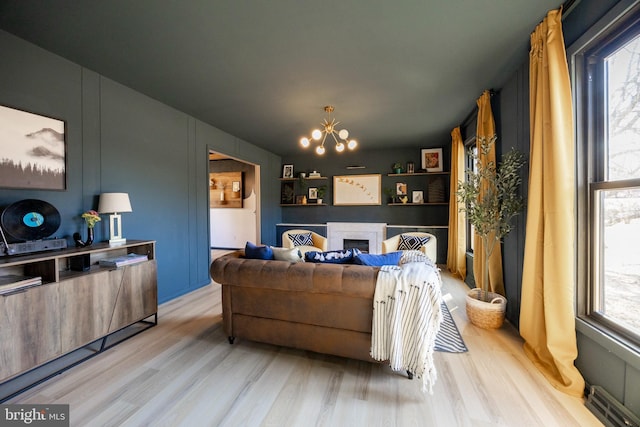 living area featuring a fireplace, an inviting chandelier, and wood finished floors