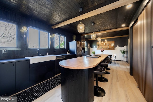 kitchen with a center island, light countertops, light wood-style flooring, freestanding refrigerator, and a sink