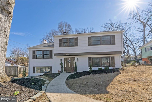 tri-level home featuring a chimney and fence