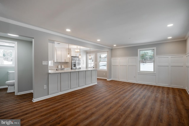 unfurnished living room featuring dark wood-style floors, ornamental molding, plenty of natural light, and recessed lighting