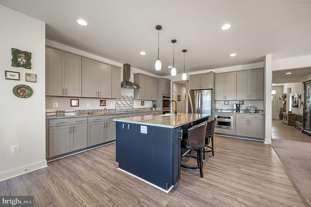 kitchen with light wood finished floors, wall chimney exhaust hood, and gray cabinetry