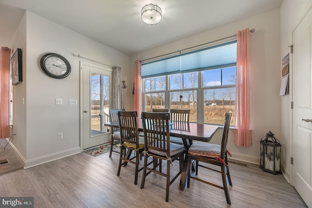 dining room featuring light wood-type flooring, visible vents, and baseboards