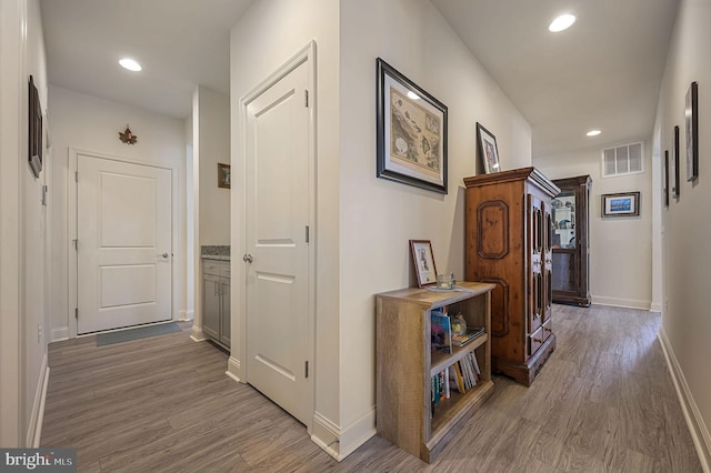 hallway with recessed lighting, visible vents, baseboards, and wood finished floors