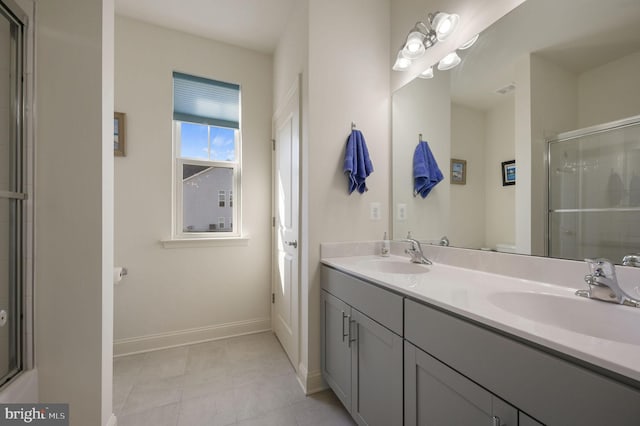 full bath with double vanity, a shower with door, baseboards, and a sink