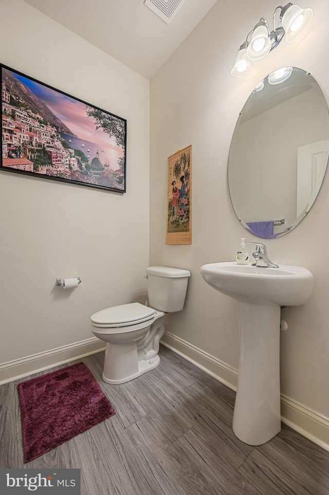 bathroom with toilet, wood finished floors, visible vents, and baseboards