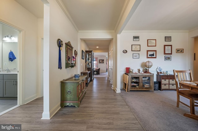 hall featuring ornamental molding, wood finished floors, a sink, and baseboards