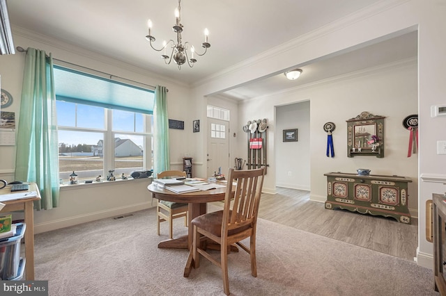 carpeted dining area featuring baseboards, visible vents, ornamental molding, wood finished floors, and a notable chandelier