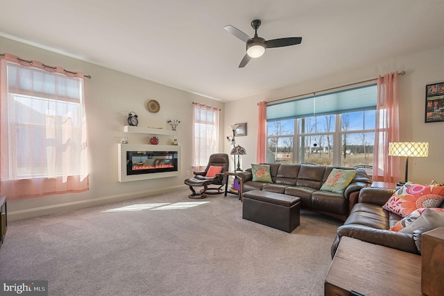 living room featuring carpet, a glass covered fireplace, a ceiling fan, and baseboards